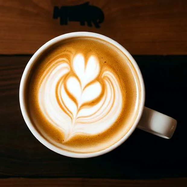 Cokelat panas dengan latte art di atas meja kayu